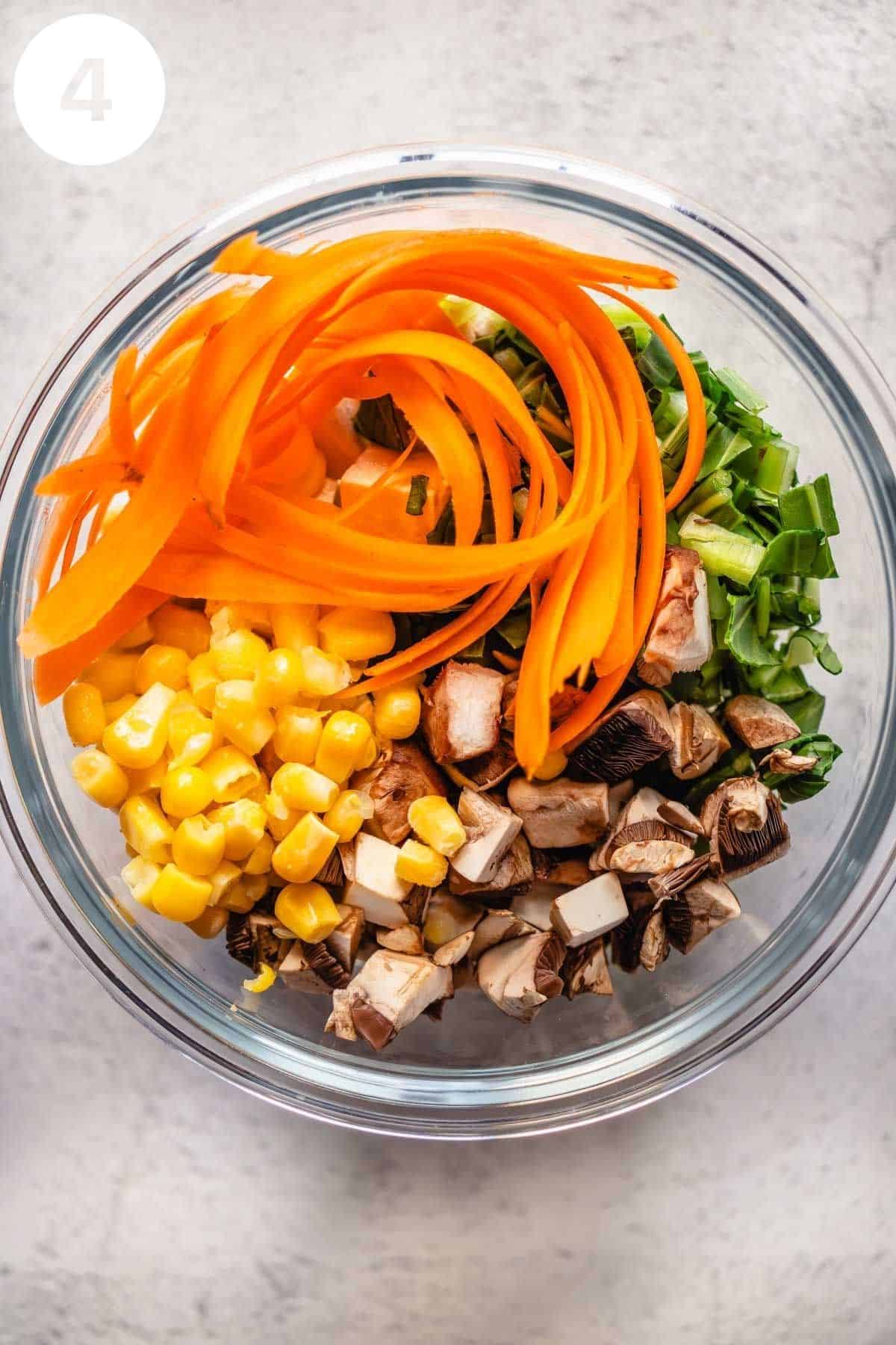 Carrot, mushrooms, corn, and bok choy in a glass meal prep container.