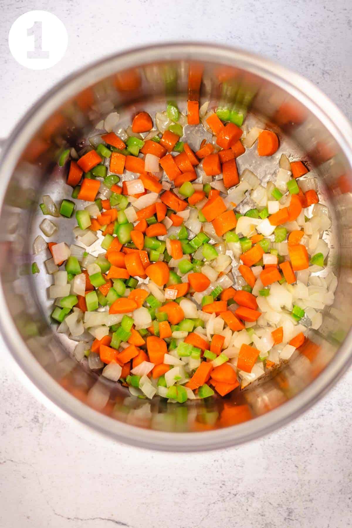Large soup pot with diced onion, carrot and celery. Labeled with a "1" in the upper left corner.
