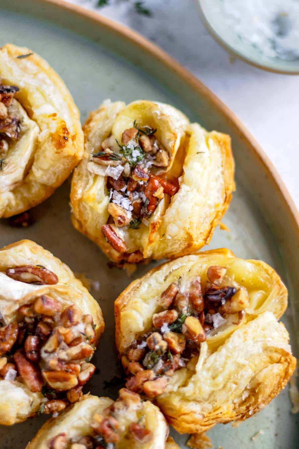 Baked brie puff pastry bites with jam arranged on a serving dish.