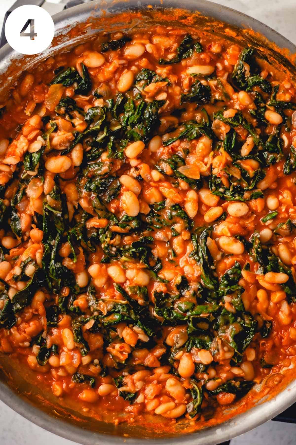 Skillet of white beans and greens in tomato sauce after the liquid has reduced and the cheese and lemon juice are stirred in. There is a number "4" in the upper left corner.