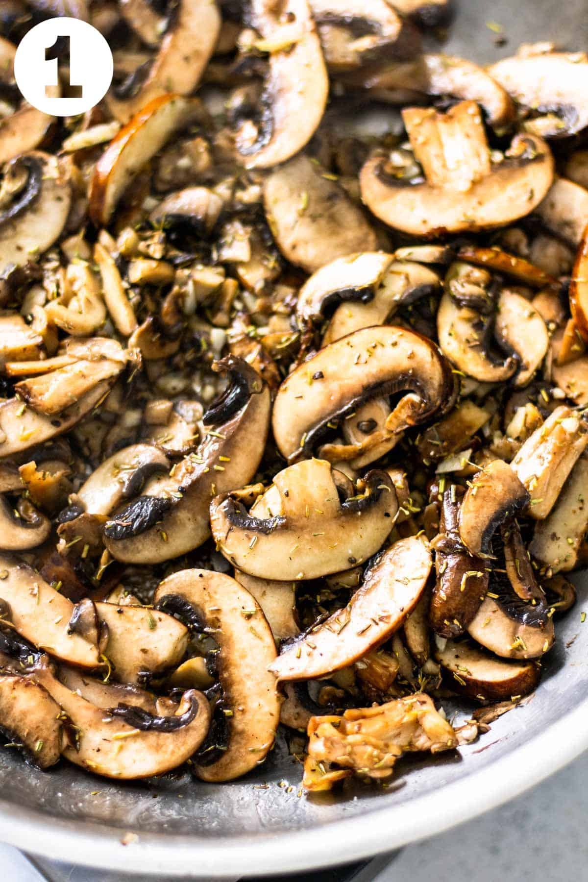 Sliced mushrooms with rosemary and thyme cooking in a skillet.