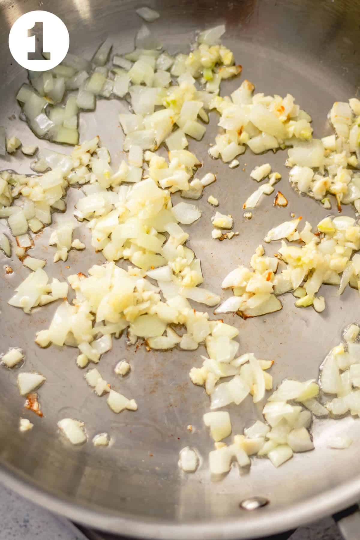 Diced onion and minced garlic cooking in a large skillet.