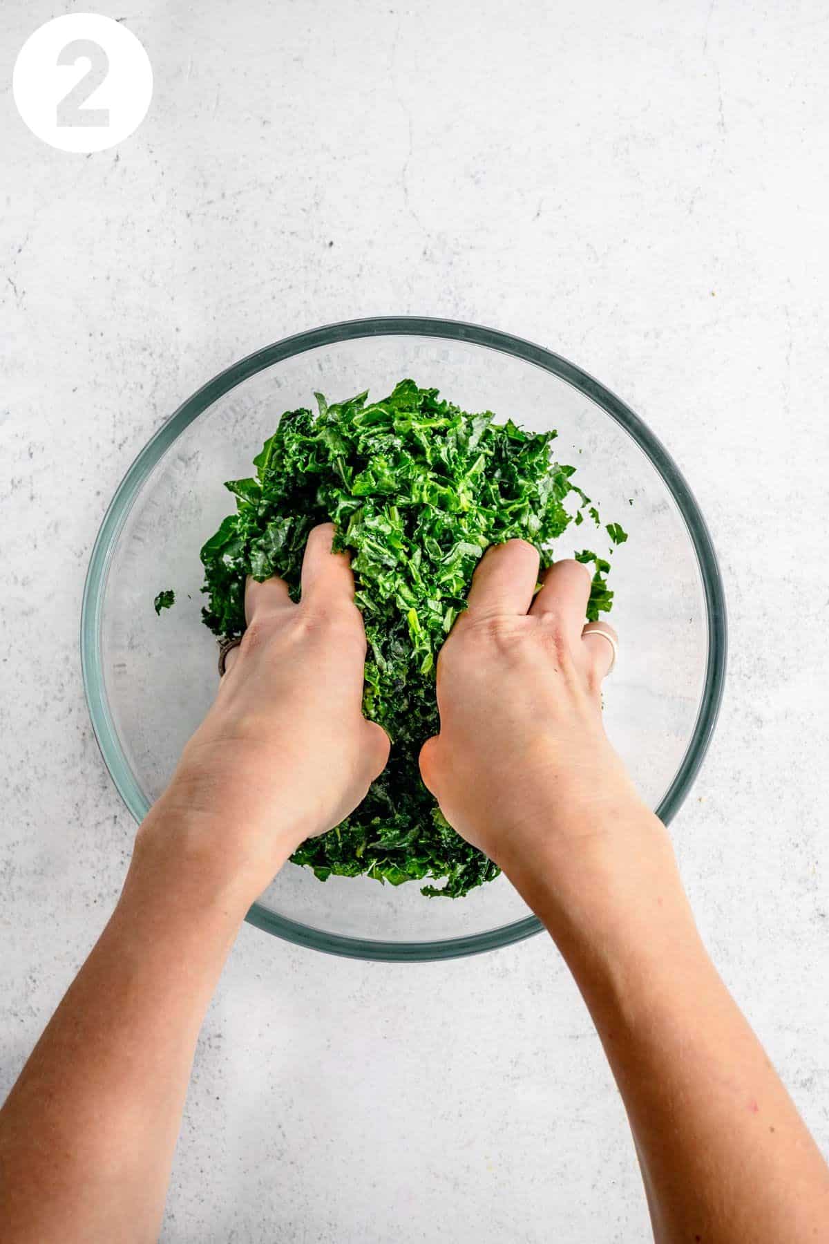 Massaging kale in a glass bowl.