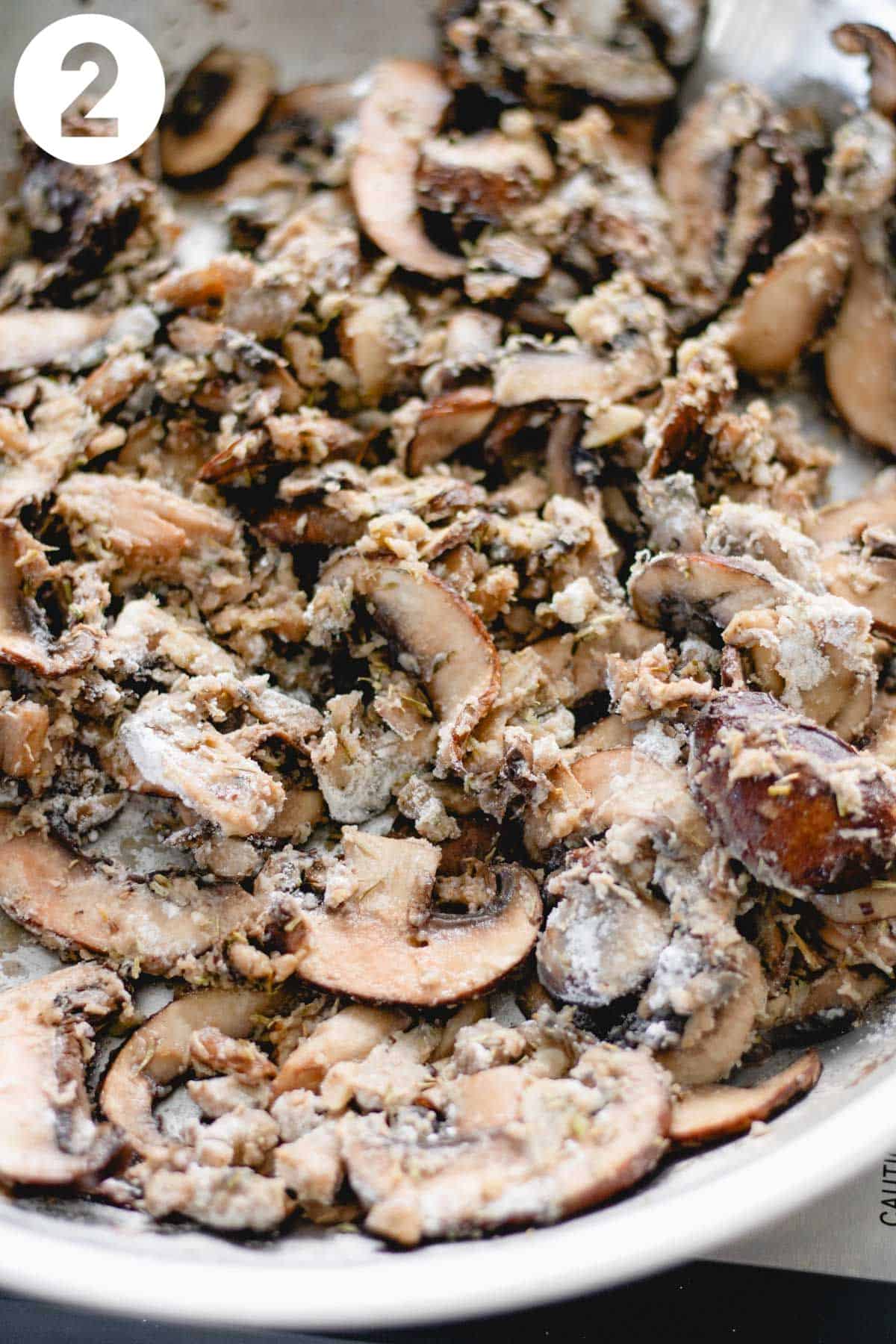 Sliced mushrooms coated with flour in a skillet.