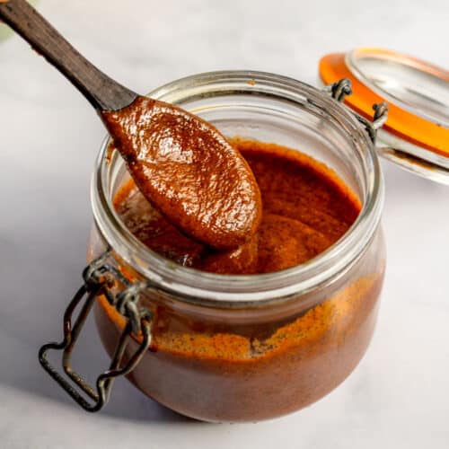 Enchilada sauce in a jar with a wooden spoon