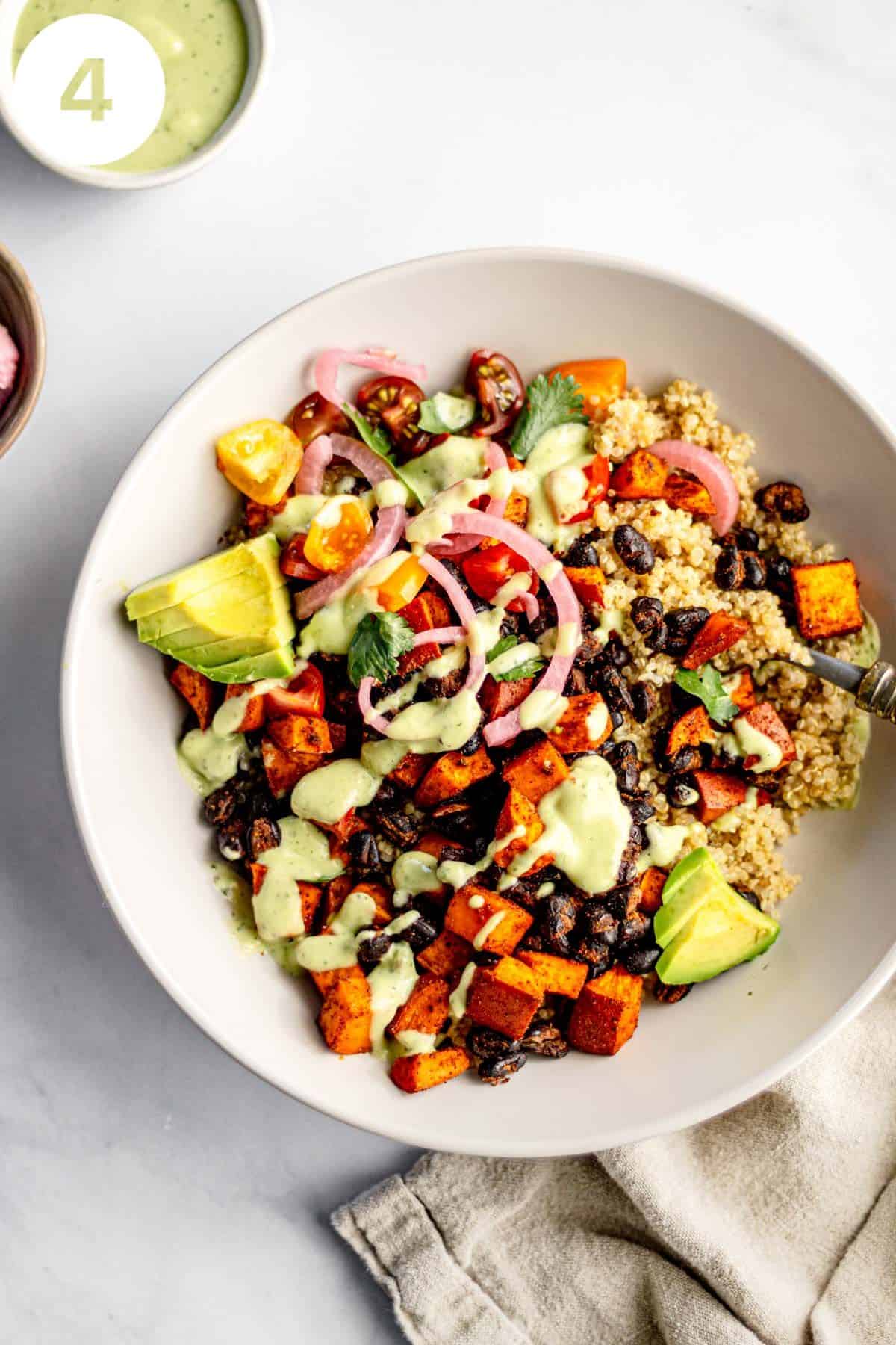 Plated quinoa bowl with sweet potatoes, black beans, avocado dressing, and garnishes. Labeled with a "4" in upper left corner.