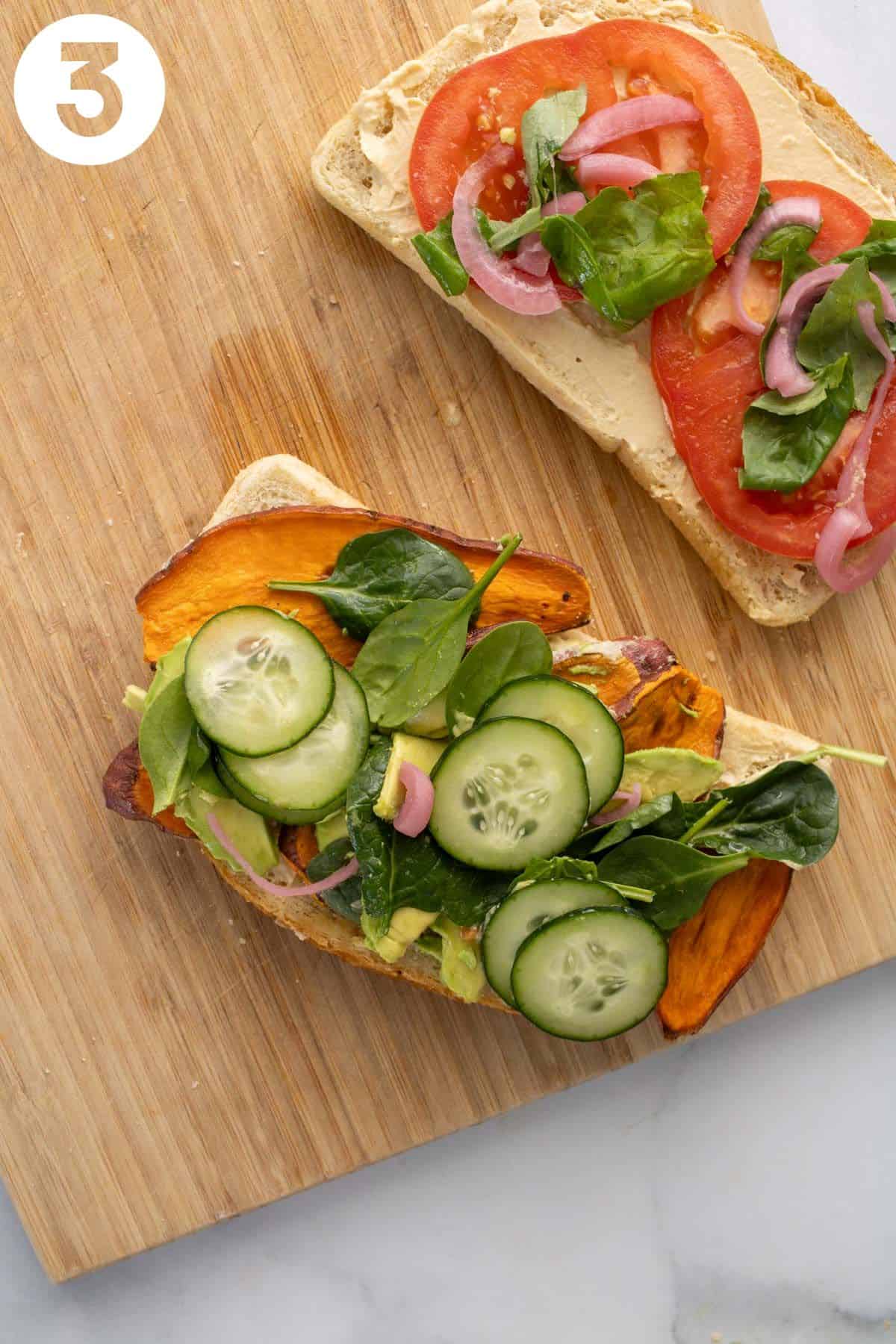 Veggie hummus sandwich with sweet potato, avocado, and cucumber open-faced on a wood cutting board. Labeled 
