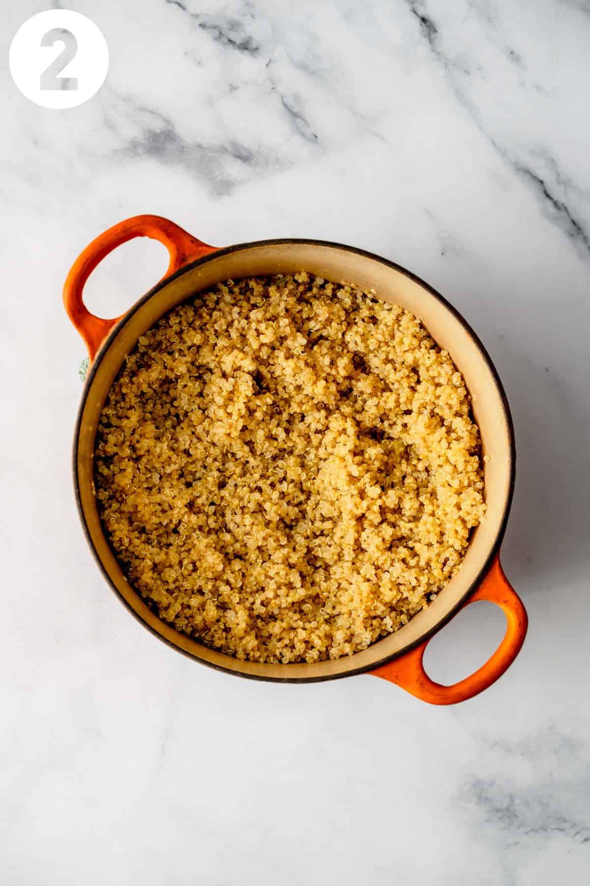 Cooked quinoa in an orange pot. Labeled with a 