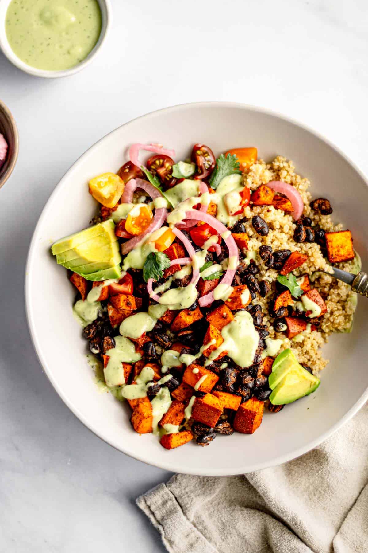 Quinoa bowl with roasted sweet potato and black beans served with avocado dressing.