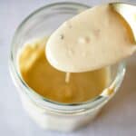A spoonful of tahini sauce held over the jar.