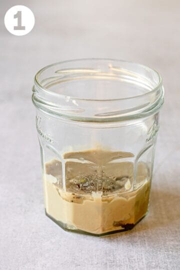 Unmixed tahini sauce ingredients in a jar. Labeled "1."