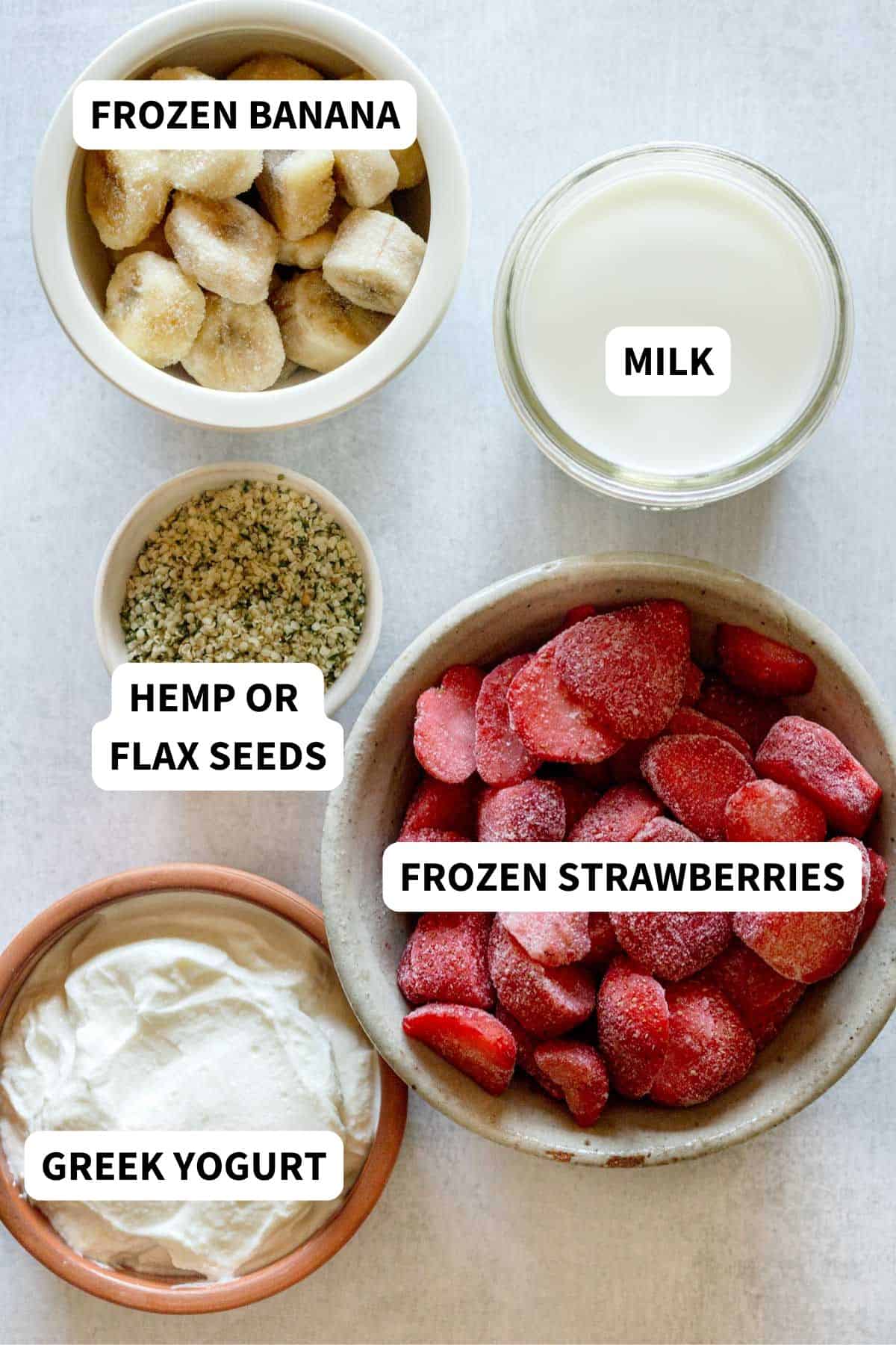Labeled ingredients to make a strawberry banana smoothie with Greek yogurt.