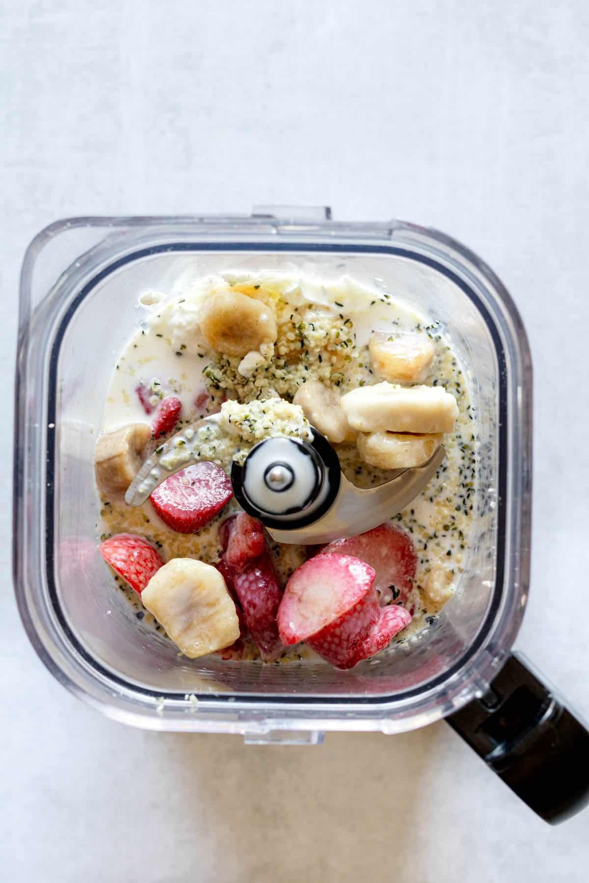 Unblended strawberry banana smoothie ingredients in a blender.