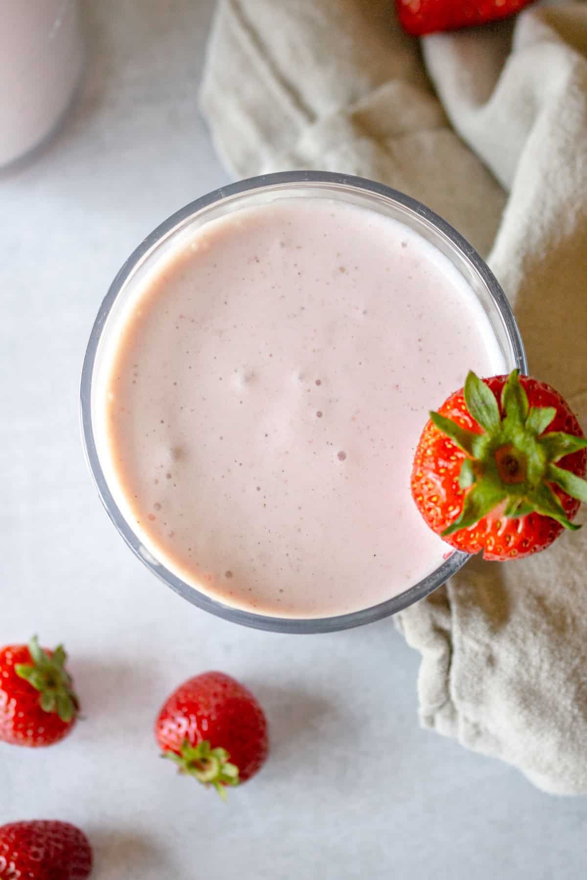 Strawberry Banana Smoothie in a glass garnished with a fresh strawberry.
