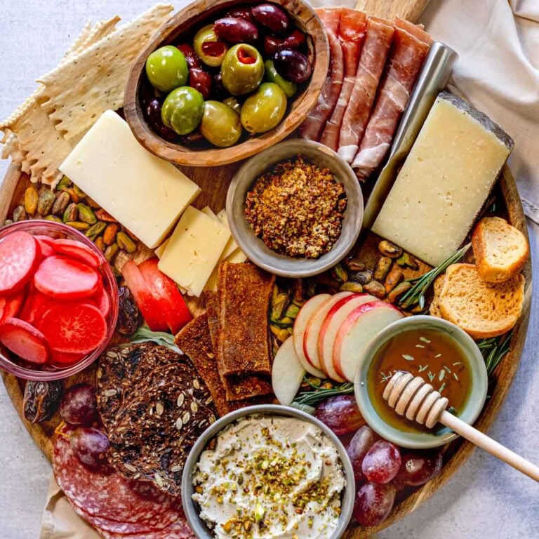 Vegetarian-friendly charcuterie board with cheese, meat, tofu, fruit, and pickled radishes.