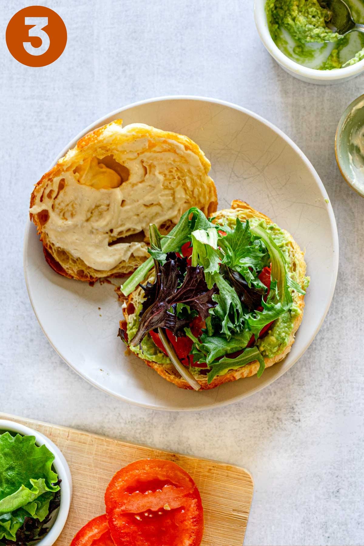 Open croissant with spring mix and sliced tomato.