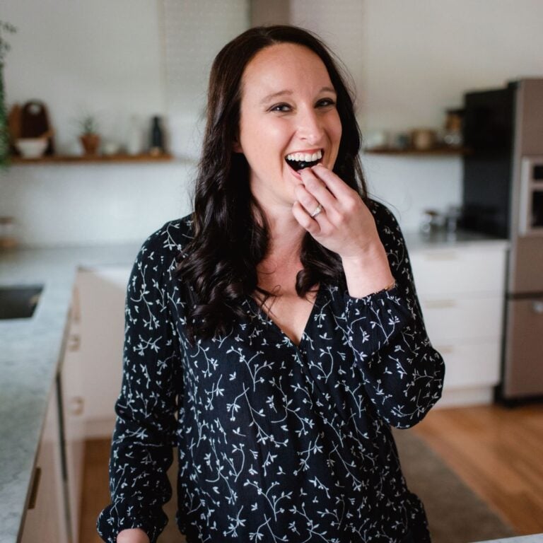 Stephanie eating and smiling in a kitchen.