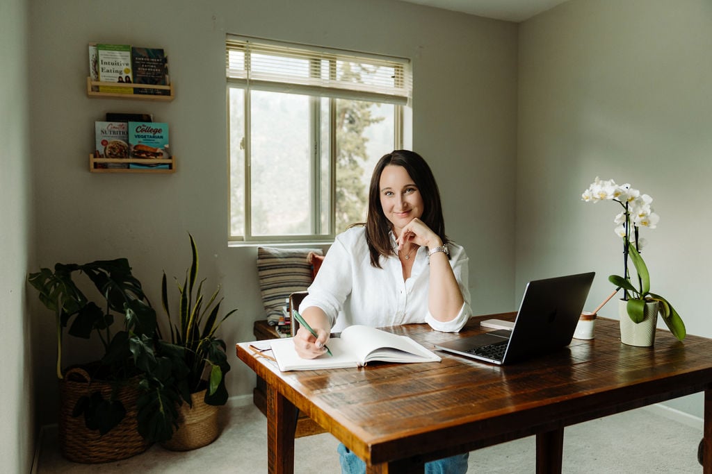 Stephanie McKercher, registered dietitian and certified intuitive eating counselor, sitting at her desk with a notebook and laptop.